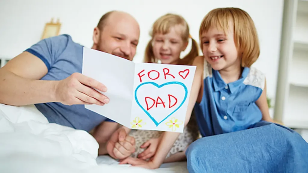 Image of a father receiving a handmade card from his children with a heart and message saying for dad