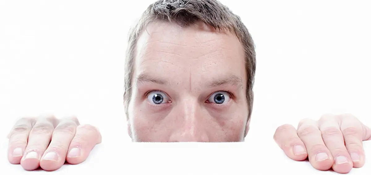Image of a man peeking over a surface with a fearful expression related to fear of mice