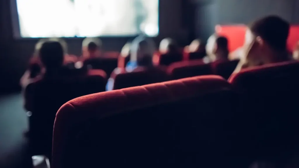Image of a movie theater audience seated and watching a film with a blurred background