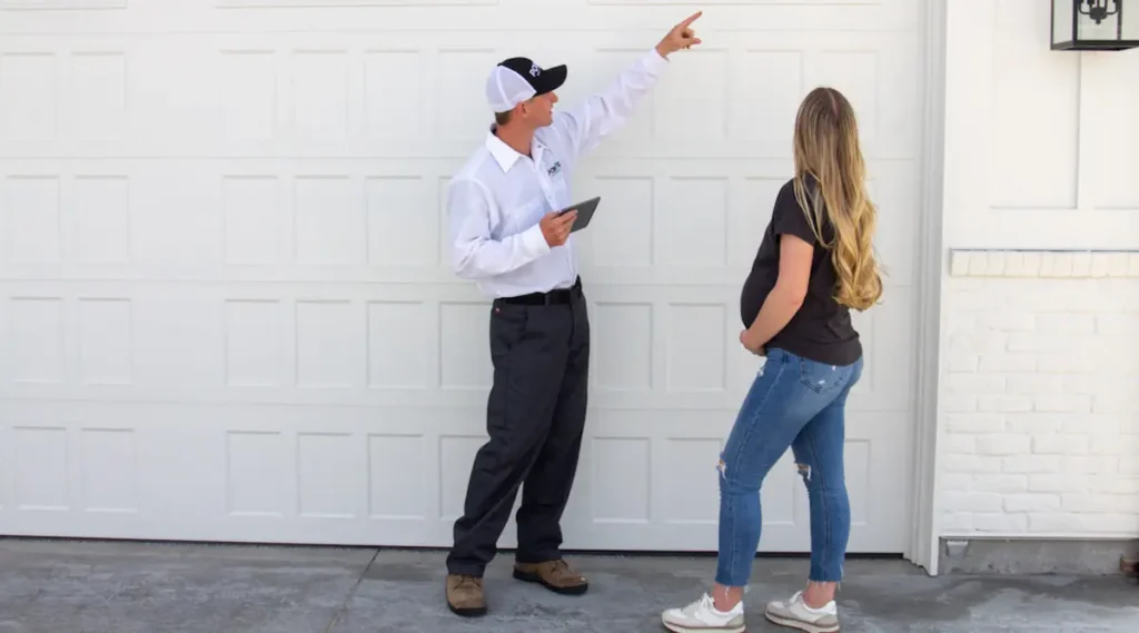Image of a pest control technician inspecting a home exterior while discussing with a homeowner
