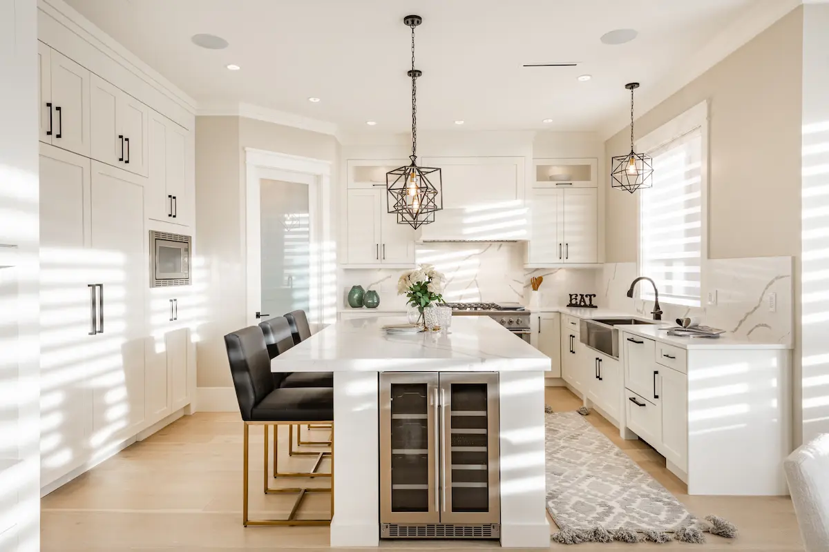 Modern white kitchen with island seating, pendant lighting, built-in cabinets, and marble backsplash