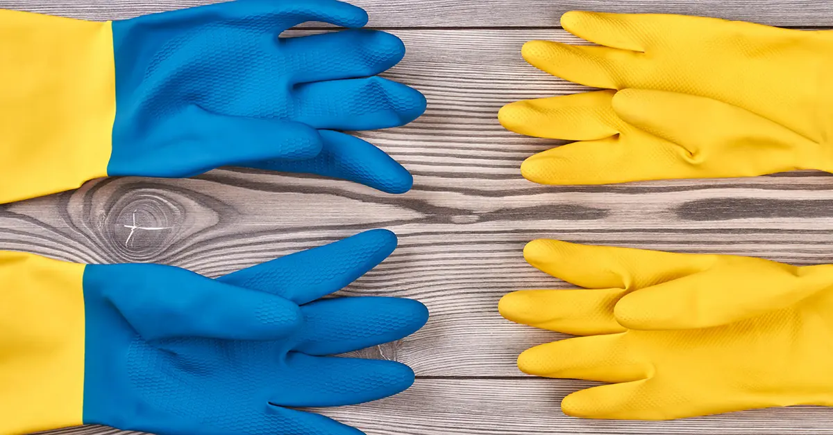 Image of blue and yellow rubber cleaning gloves arranged on a wooden surface